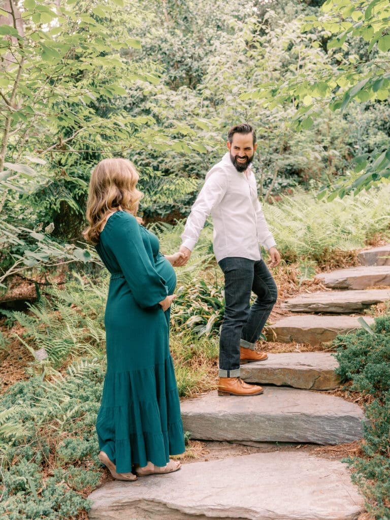 Expectant couple walking hand in hand through Duke Gardens during a spring maternity photography session in Durham, NC
