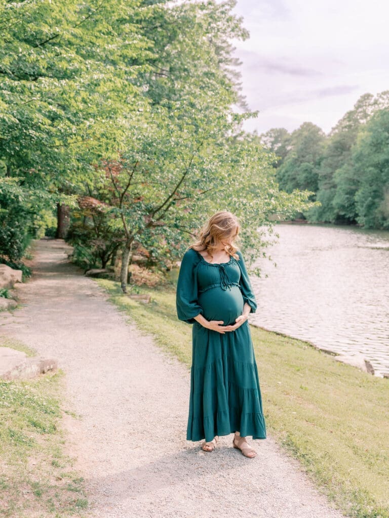 Pregnant mother standing along a lakeside path at Duke Gardens during an outdoor maternity session in Durham, NC