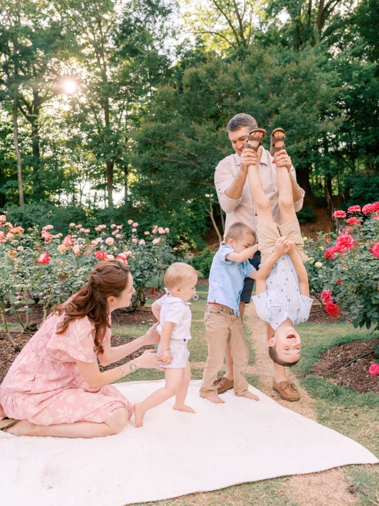 Family playing together among blooming roses while preparing to welcome a new baby in Raleigh