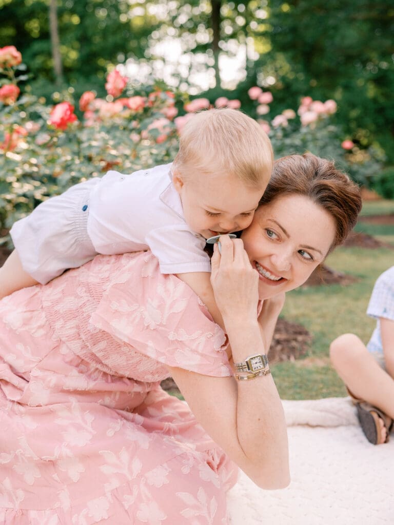 Young toddler cuddling his mother during a natural family maternity session at the Raleigh Rose Garden