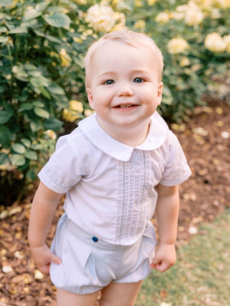 Smiling young boy standing in front of yellow roses at the Raleigh Rose Garden