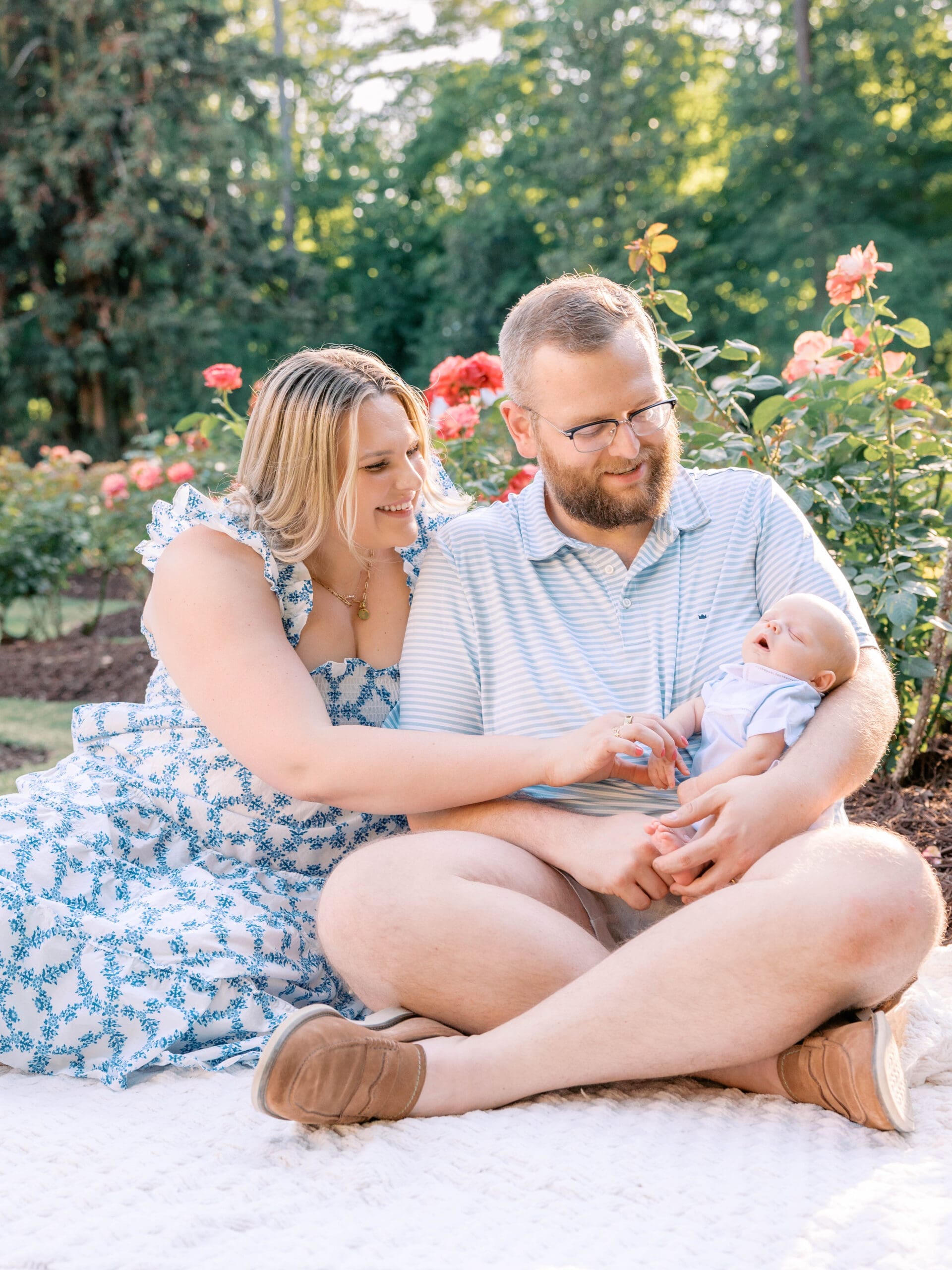 Parents cuddling their newborn baby boy during a Raleigh Rose Garden newborn photography session.