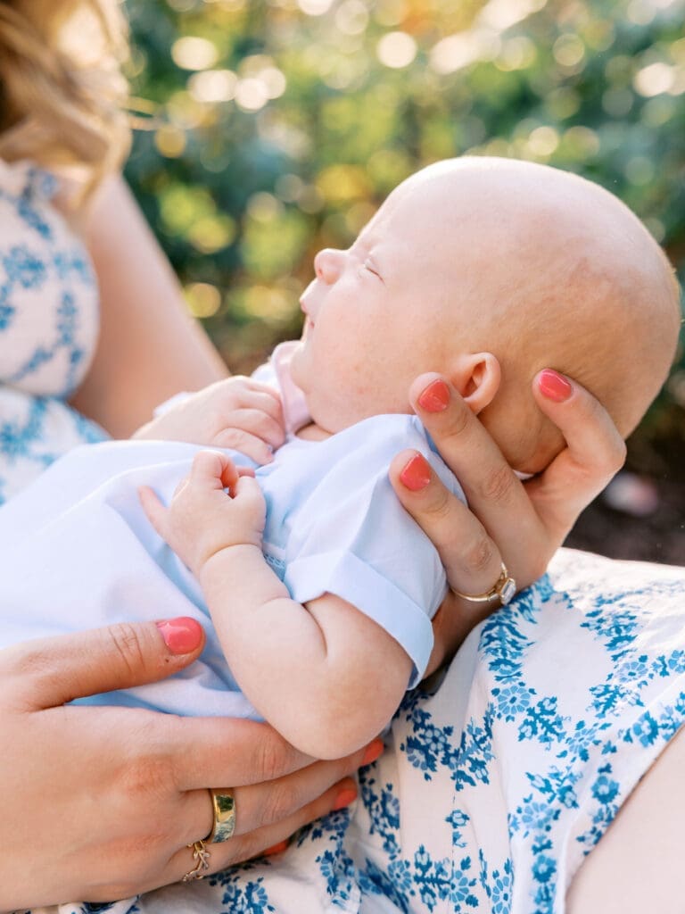 Mother holding her newborn baby during an outdoor newborn session at Raleigh Rose Garden.

